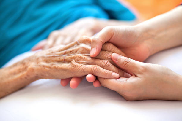 Hands of an elderly person held by younger hands